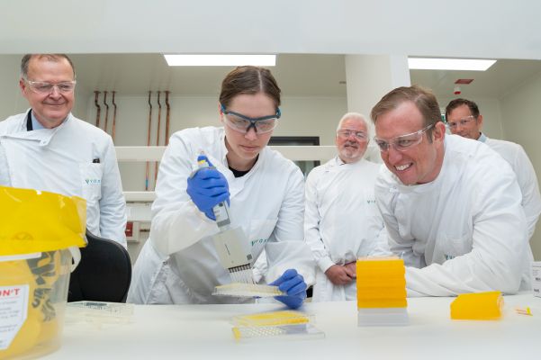 People standing in PPE gear watching medical tests