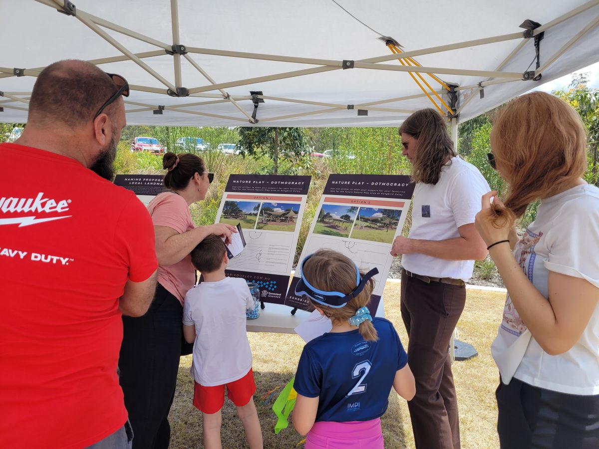 group of people reviewing information boards in a park